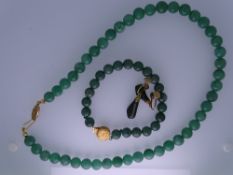 A JADE NECKLACE ENSEMBLE - a dark green jade bead necklace with yellow metal, believed nine carat