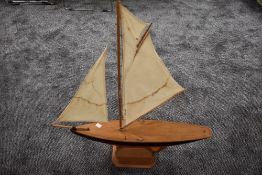 A hand made wooden model sail boat on stand