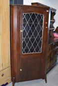 An early 20th Century stained frame corner display with lower cupboard section