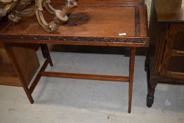 An Arts and Crafts oak tray table, having extensive foliate carving on plain frame, approx. 87 x