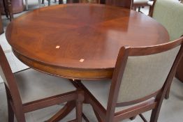 A reproduction Regency style circular dining table and four (3 and 1) dralon upholstered dining