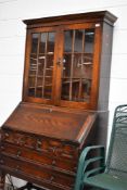 An early 20th Century oak bureau bookcase , having Jacobean inspired cushioned two over two drawers