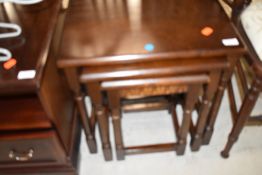 A dark stained oak nest of three tables
