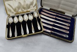 A cased set of six butter knives having white metal handles, marks worn and a cased set of six HM