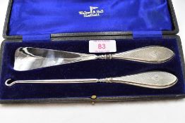 A cased silver handled shoe horn and button hook having engine turned decoration and bearing