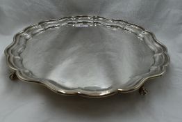 A silver salver of plain form having pie crust rim and quatrefoil ball and claw feet, Sheffield