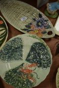 A plate in the shape of a leaf with hand painted floral design to end with embossed basket weft