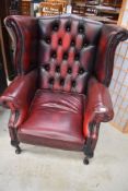 A burgundy leather button back wing armchair, little bit of heat damage to left arm hence the low