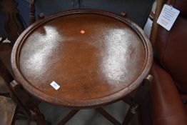 An early to mid 20th Century oak tray table, on folding frame, circular top reverses to make games