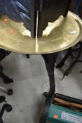 An Oriental or Islamic brass tray top table, having dark fretwork frame