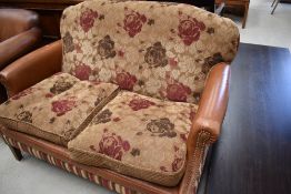 A modern part brown leather two seater settee of small proportions, approx. width 125cm