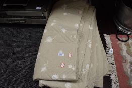 A large modern bed throw having rose print on a beige background.