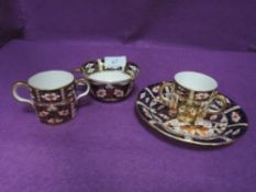 A Royal Crown Derby cup and saucer and two loving cups, one having two handles and the other