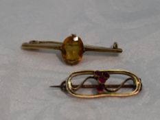 A small 9ct gold brooch of open oval form having central rubies, and a yellow metal bar brooch