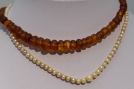 A string of facetted Baltic amber graduated beads and a string of graduated cultured pearls