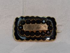 A Victorian mourning brooch of rectangular form having black enamel decoration to yellow metal mount