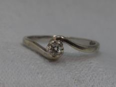 A lady's diamond solitaire dress ring, approx 0.1ct in a raised claw mount to crossover shoulders on