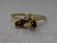 A lady's dress ring having a trio of diamond and rubies in a stylised mount on an 18ct gold loop,