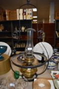 A large vintage brass oil or paraffin lamp with a cast metal ceiling mount.