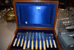 A mahogany canteen lined in blue housing a selection of fish knifes and forks.