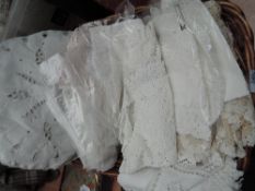 A basket containing various lace and crotchet pieces, including collars, cuffs,doilies and cloths,
