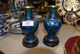 A small pair of Cloisonné vases on wooden stands in blue and green tones.