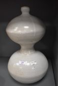 A vintage stone ware studio pottery vessel or lamp base with white glaze and gourd design