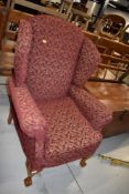 A reproduction wing back armchair , on cabriole legs with ball and claw feet