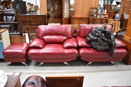 A pair of vintage style red leather armchairs and matching footstool, on chrome legs