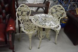 A modern cast and painted garden table and pair of similar chairs, rose design