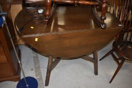A dark stained Ercol drop leaf table and set of six moustache back chairs