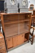 A vintage Ladderax style teak bookcase, having glazed upper section over double sliding door