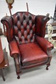 A traditional burgundy leather wing back armchair