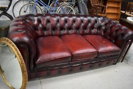 A traditional burgundy leather chesterfield settee