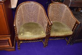A pair of early 20th Century canework tub chairs having oak twist frames