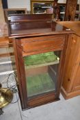 A late 19th or early 20th Century mahogany music cabinet having lift top, glazed door and lined