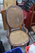 An early 20th Century stained frame salon chair having bergere canework seat and back