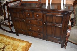 A dark stained Ercol sideboard, having central section of two short over three long drawers, flanked