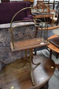 An antique oak and brass paper rack, having triple splay brass legs