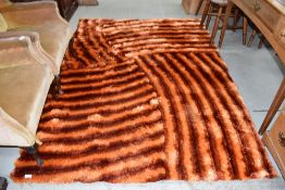 A modern designer carpet square by the Rug shop in shades of orange and red