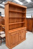 A traditional pine dresser with open shelves over double cupboard base, approx. dimensions width