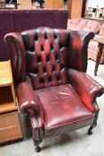 A burgundy leather button back wing armchair, little bit of heat damage to left arm hence the low