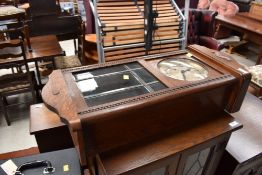 A wall mounted pendulum clock with glass window and chime