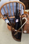 An Edwardian oak framed stick stand with a selection of walking sticks and umbrellas