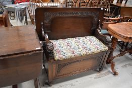 An early 20th Century oak monks bench having lion arms, on shepherds casters, width approx. 106cm