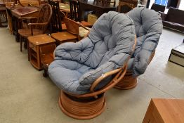 Two vintage 80's style bamboo lounge or conservatory chairs having rotating bases