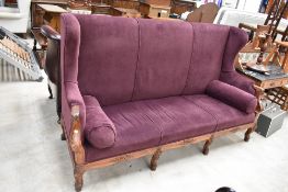 A large French or low country wing back settle, having later plum upholstery, a great statement