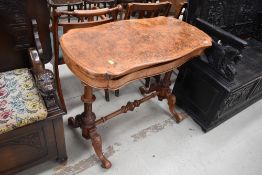 A 19th Century walnut fold over tea table having turned and carved frame, veneers lifting quite