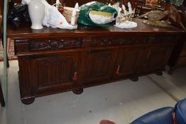 A traditional oak long sideboard, having carved frieze drawers and linen fold cupboards, width