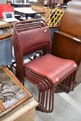 A set of six vintage stacking chairs, having read leather seats and tubular metal frames
